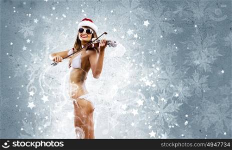Girl violinist. Young Santa girl in bikini playing violin
