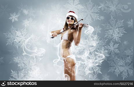 Girl violinist. Young Santa girl in bikini playing violin