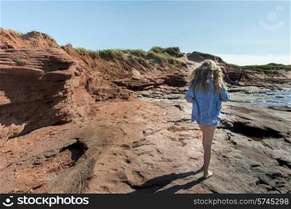 Girl walking along coastline, Cavendish Beach, Green Gables, Prince Edward Island, Canada