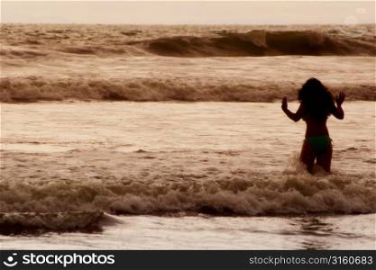 Girl walking in to sea and waves