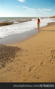 Girl walking on the beach. Peaceful scene.