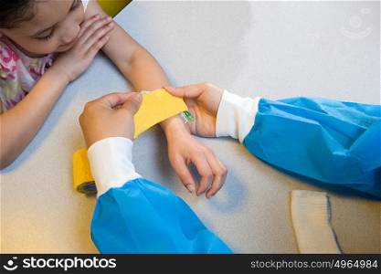 Girl watching nurse put bandage on her arm