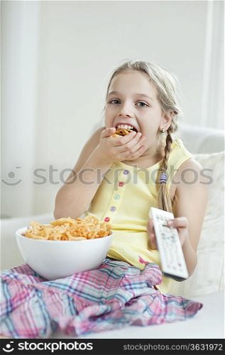 Girl watching TV as she stuffs her mouth with wheel shape snack pellets