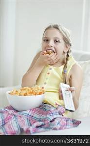 Girl watching TV as she stuffs her mouth with wheel shape snack pellets