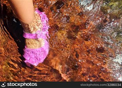 Girl water feet pink shoe in river stream red bottom rolling stones