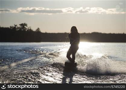 Girl waterskiing with the glow of sunlight behind her, Lake of The Woods, Ontario, Canada