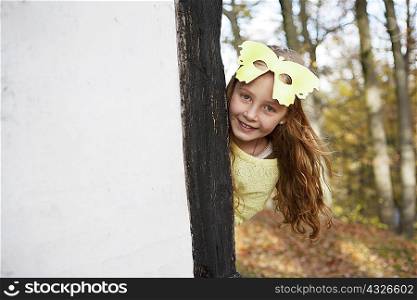 Girl wearing butterfly mask outdoors