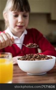 Girl Wearing School Uniform Eating Bowl Of Sugary Breakfast Cereal In Kitchen