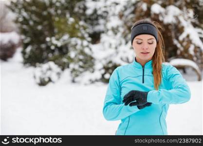 Girl wearing sportswear and looking at watch. Winter sports, outdoor fitness, fashion, workout, health concept.. Winter workout. Girl wearing sportswear, looking at watch