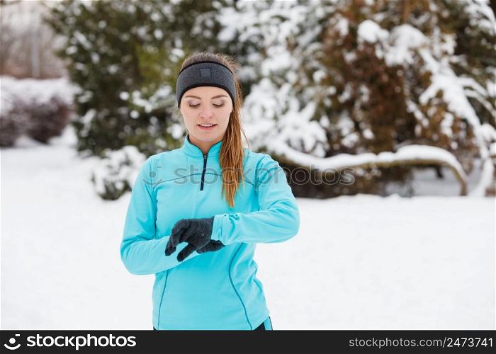 Girl wearing sportswear and looking at watch. Winter sports, outdoor fitness, fashion, workout, health concept.. Winter workout. Girl wearing sportswear, looking at watch