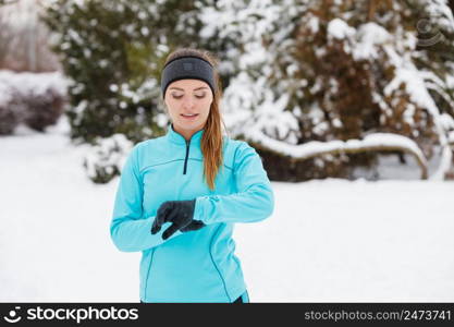 Girl wearing sportswear and looking at watch. Winter sports, outdoor fitness, fashion, workout, health concept.. Winter workout. Girl wearing sportswear, looking at watch