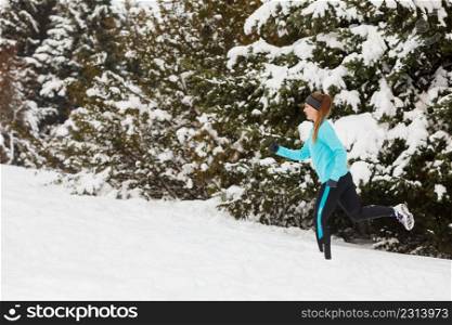 Girl wearing sportswear and running on snow with trees in background. Winter sports, outdoor fitness, workout, health concept.. Running girl wearing sportswear, winter fitness