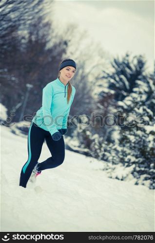 Girl wearing sportswear and running on snow with trees in background. Winter sports, outdoor fitness, workout, health concept.. Running girl wearing sportswear, winter fitness