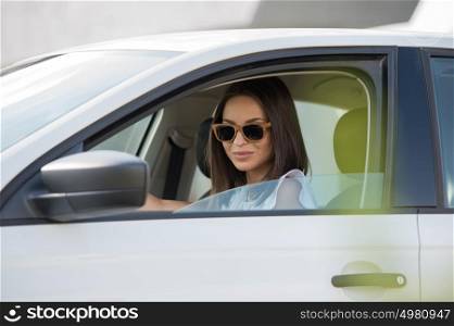 Girl wearing sunglasses driving white car