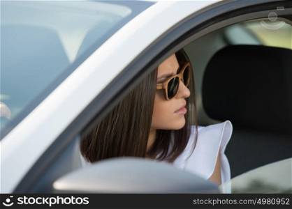 Girl wearing sunglasses driving white car