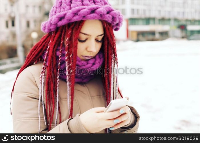 Girl wearing winter clothing, uses mobile phone