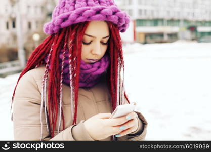 Girl wearing winter clothing, uses mobile phone