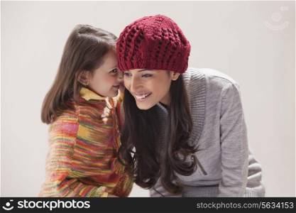 Girl whispering in mother&rsquo;s ear