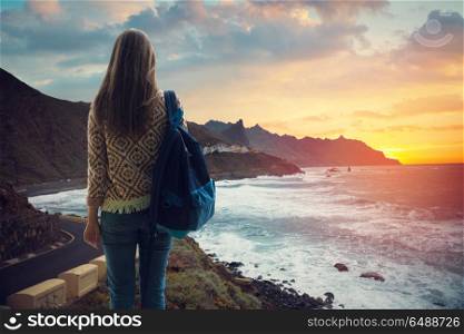 girl with a backpack looking at the city on the coast at sunset. Canary Spain
