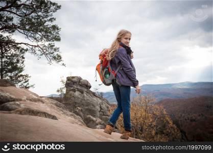 girl with a backpack stands on Dovbush rocks at the Carpathians, Ukraine