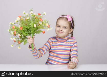 Girl with a bouquet of artificial flowers sitting at the table