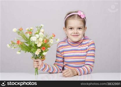 Girl with a bouquet of artificial flowers sitting at the table