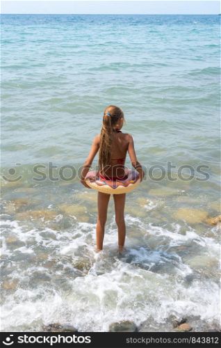 Girl with a circle goes swimming in the sea