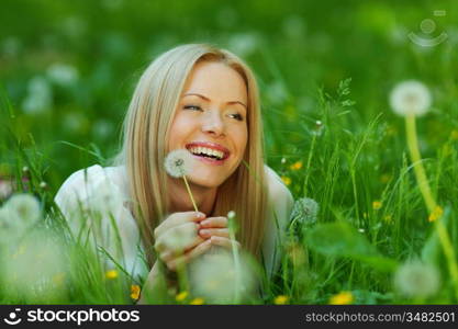 girl with a dandelion in his hand lying on the grass