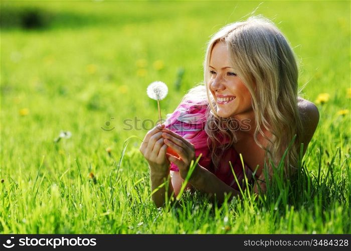 girl with a dandelion in his hand lying on the grass