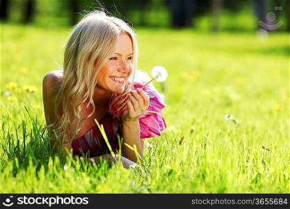 girl with a dandelion in his hand lying on the grass