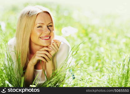 girl with a dandelion in his hand lying on the grass. girl with a dandelion