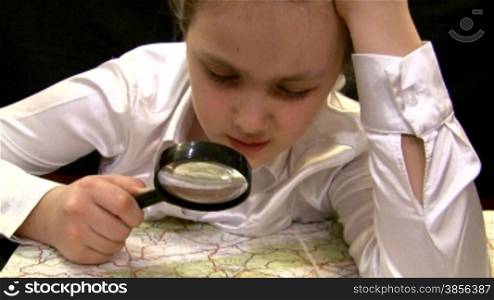 girl with a magnifier studies a map of Europe.