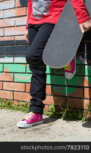 Girl with a skateboard next to a graffiti wall