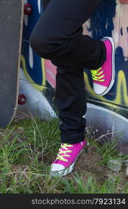 Girl with a skateboard next to a graffiti wall