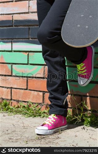 Girl with a skateboard next to a graffiti wall