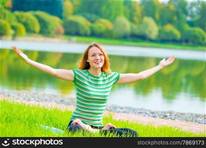 girl with a smile in the lotus position with arms outstretched to the sides