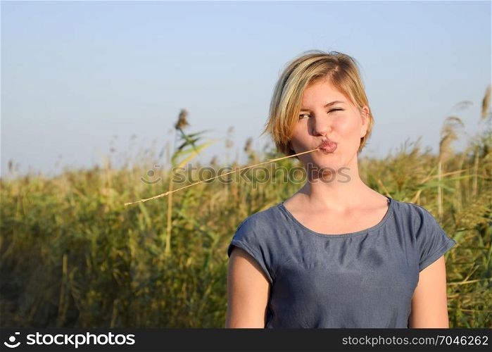 girl with a straw in her mouth against a background of reed thickets.. girl with a straw in her mouth against a background of reed thickets