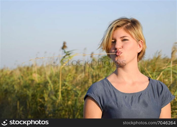 girl with a straw in her mouth against a background of reed thickets.. girl with a straw in her mouth against a background of reed thickets