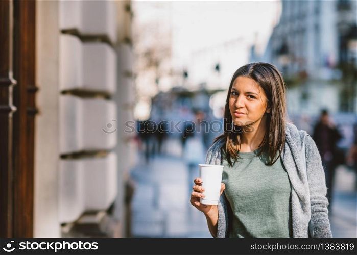 Girl with a take-away coffe in the city looking storesand shopping