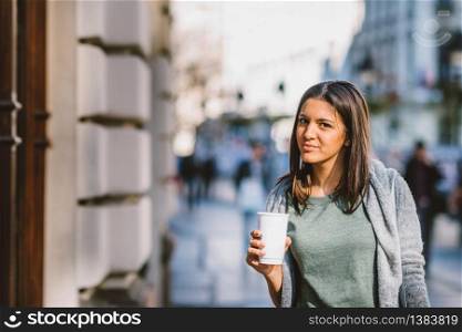 Girl with a take-away coffe in the city looking storesand shopping