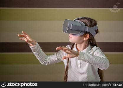 Girl with a virtual reality headset. The girl explores the world of virtual reality through video and games. Technologies of the future.. Girl with a virtual reality headset. The girl explores the world of virtual reality through video and games.