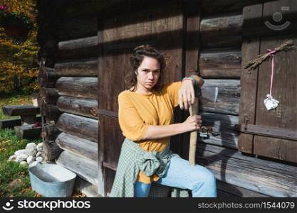 girl with an ax near a wooden house in the mountains