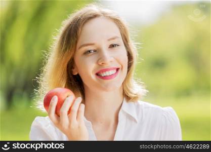 Girl with apple. Young pretty woman in summer park with apple