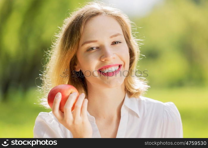 Girl with apple. Young pretty woman in summer park with apple