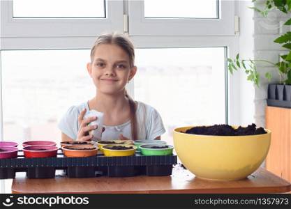 Girl with bags of seeds and pots of earth sitting at the table