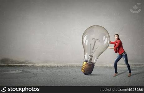Girl with big glass bulb. Young girl in red jacket pushing glass light bulb