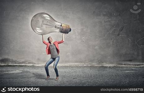 Girl with big glass bulb. Young woman lifting glass light bulb above head