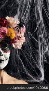 girl with black hair is dressed in a wreath of multi-colored roses and makeup is made on her face Sugar skull to the day of the Dead, close up