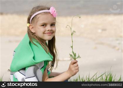 Girl with blade of grass in hands. Girl happily plucked a blade of grass for a herbarium