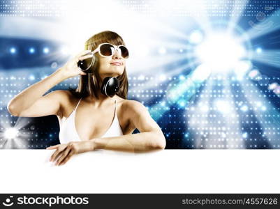 Girl with blank banner. Young woman in white bikini wearing headphones. Place for text